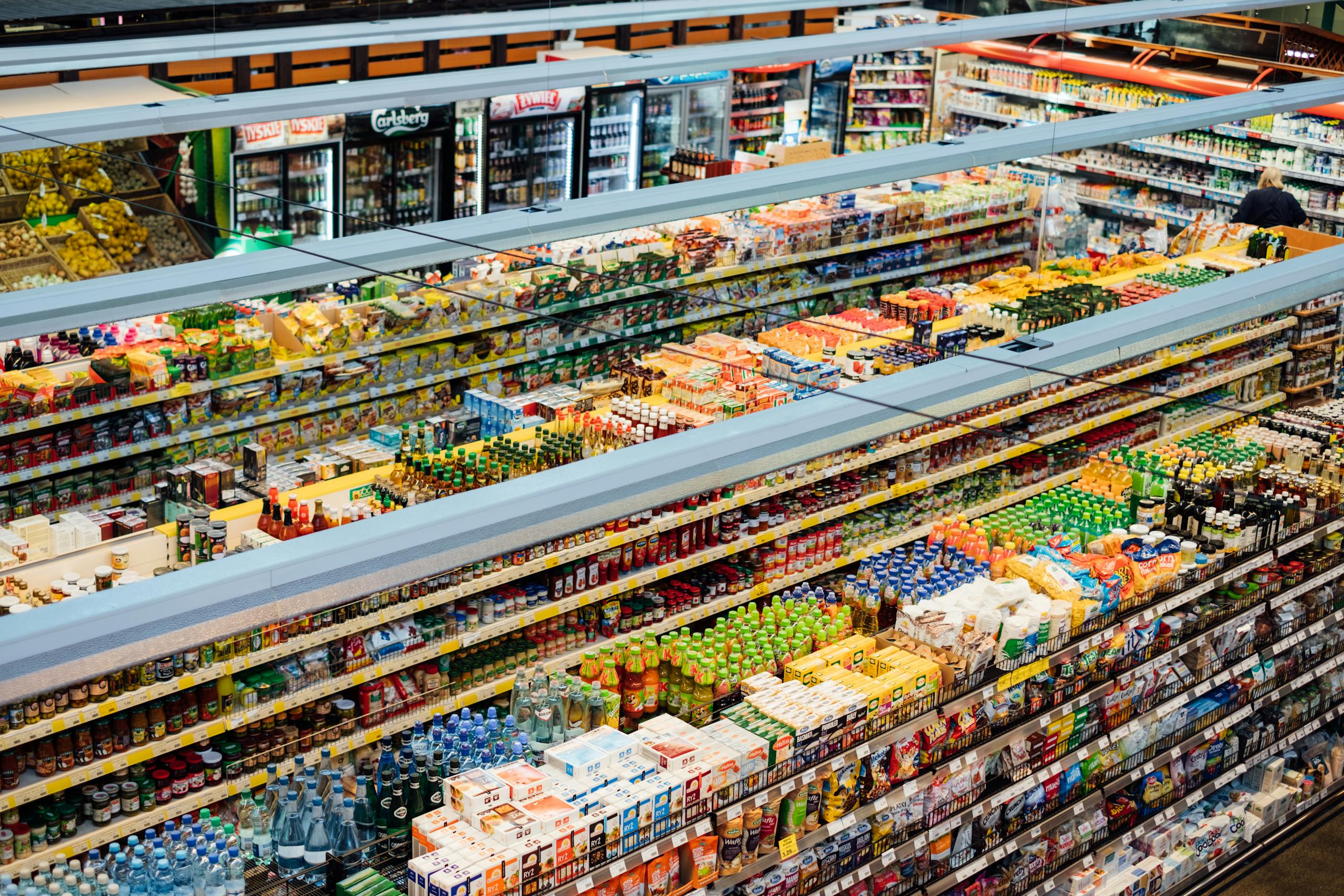 Explore the colorful, fully-stocked shelves of a bustling supermarket from above.